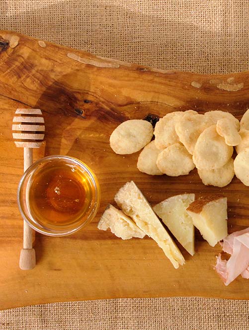 Monetine snack PANDorà su tagliere con miele, salumi e formaggi